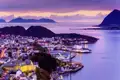 Abendlicher Blick auf die erleuchtete Jugendstilstadt Alesund in Norwegen, umgeben vom Meer.