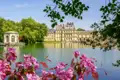 Malerischer Blick auf das Schloss Fontainebleau und seinen Karpfenteich, eingerahmt von leuchtend rosa Blüten am Ufer, welches wir auf unserer Gruppenreise mit Studiosus in die Normandie besuchen.