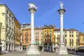 Auf unserer Gruppenreise mit Studiosus nach Italien sehen wir die Säulen mit dem Markuslöwen und der Erlöserstatue auf der Piazza dei Signori in Vicenza vor bunten Fassaden.