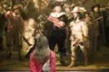 Teilnehmerin einer Studiosus Studienreise betrachtet Rembrandts berühmtes Gemälde 'Die Nachtwache' im Rijksmuseum Amsterdam.