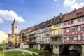 Sonnige Ansicht der bunten Fachwerkhäuser auf der historischen Krämerbrücke in Erfurt, im Hintergrund der Turm der Ägidienkirche, ein Highlight jeder Studiosus Gruppenreise.