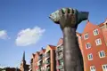 Nahaufnahme der Fisch-Skulptur auf dem Nordermarkt in Flensburg vor roten Giebelhäusern und dem Kirchturm der Marienkirche, ein Highlight unserer Rundreise mit Studiosus.