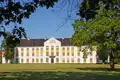 Die prachtvolle, weiße Fassade des Barockschloss Augustenborg in Dänemark, gesehen über den Schlosspark bei blauem Himmel, ein toller Ausflug auf unserer Gruppenreise mit Studiosus.