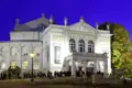 Elegant gekleidete Gäste einer Studiosus Eventreise versammeln sich am Abend vor dem beleuchteten Prinzregententheater in München.