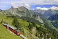 Die rote, historische Schynigge Platte-Bahn fährt auf einer Studienreise vor dem Panorama von Eiger, Mönch und Jungfrau.