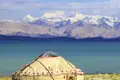 Traditionelle Jurte am Ufer des tiefblauen Issyk-Kul-Sees vor dem schneebedeckten Panorama des Tianshan-Gebirges, ein toller Ausblick auf unserer Gruppenreise mit Studiosus.