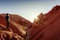 Eine Reisende blickt bei Sonnenaufgang auf die bizarren, roten Felsformationen im berühmten Skazka-Canyon in Kirgisistan, ein tolles Erlebnis auf unserer Rundreise mit Studiosus.