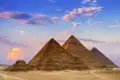 Die Pyramiden von Gizeh in Ägypten bei Sonnenuntergang mit Kamelen im Vordergrund.