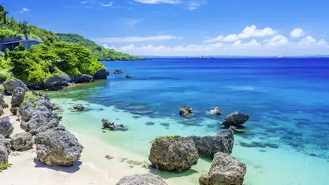 Idyllische Küstenlandschaft auf Okinawa mit Felsen, Sandstrand und smaragdgrünem Meer, ein Highlight der Studiosus Studienreise nach Japan.