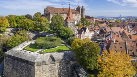 Die historische Kaiserburg thront über der Nürnberger Altstadt, umgeben von den Burggärten und herbstlich gefärbten Bäumen.