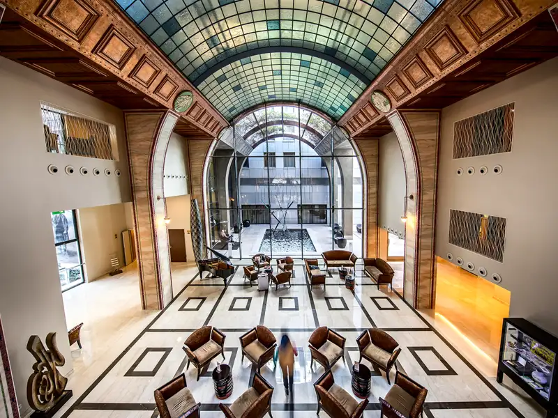 Blick von oben in das lichtdurchflutete Atrium des Continental Hotels in Budapest mit seiner prächtigen Jugendstil-Glaskuppel.