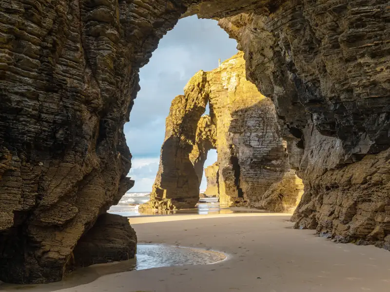Der Strand der Kathedralen von Ribadeo präsentiert sich uns auf unserer Gruppenreise mit Studiosus bei Ebbe besonders eindrucksvoll: Wind und Wetter meißelten an den Felstoren, die sich wie gotische Strebebögen an die Küste anlehnen.