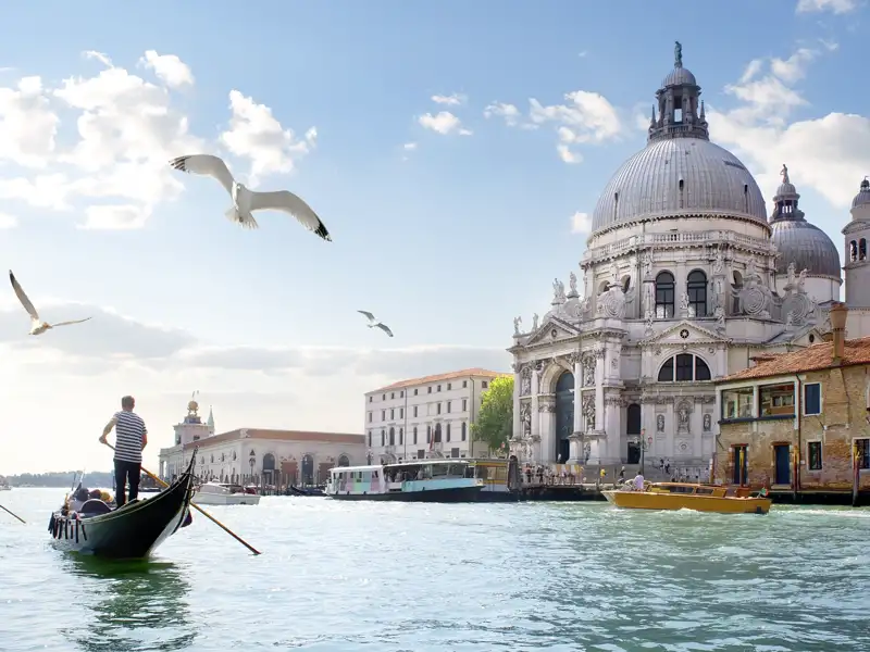 Gondolieri auf dem Canal Grande werden Ihnen auf der Städtereise nach Venedig immer wieder begegnen: hier mit der Kirche Santa Maria della Salute im Hintergrund.