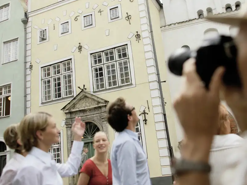 Touristen besichtigen und fotografieren die Drei Brüder, ein historisches Gebäudeensemble in Riga.