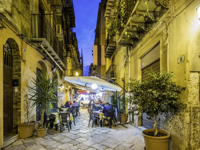 Abendliche Restaurantszene in einer engen Gasse.