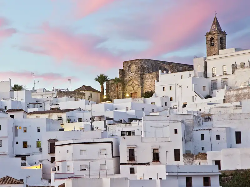 Auf unserer Rundreise durch Andalusien für Singles und Alleinreisende erfreuen wir uns an den terrassenförmig angelegten Weißen Häusern in Vejer de la Frontera mit der Kirche ganz oben, hier im Abendlicht.