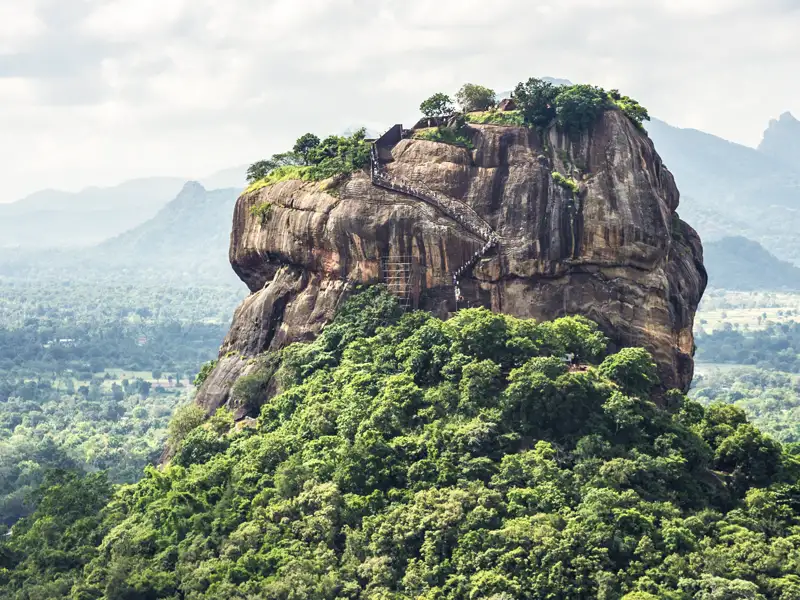 Auf unserer Rundreise durch Sri Lanka erklimmen wir die vielen Treppenstufen, die zum Löwenfelsen Sigiriya hinaufführen. Auf halbem Weg besuchen wir die Freskenmalerei der Wolkenmädchen.