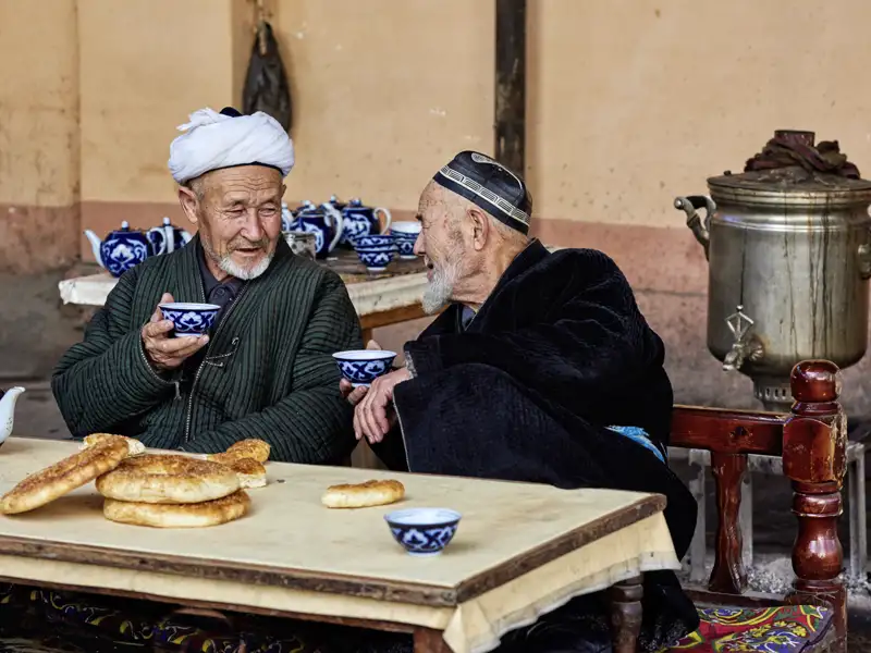 Auf unserer Studienreise Usbekistan - Tagträume im Märchenland treffen wir immer wieder Einheimische. Die blauen Teeschälchen mit Baumwollmuster sind typisch für Usbekistan, die kreisrunden Fladenbrote ebenso.
