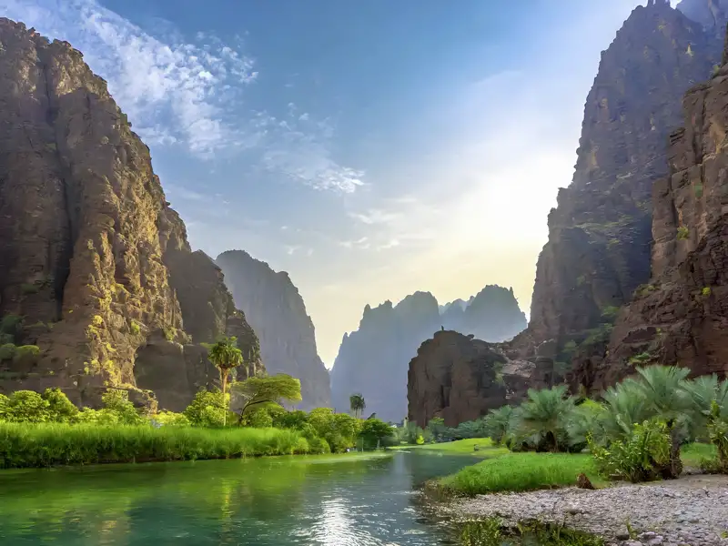 Mit Geländewagen geht es bei unserer Studiosus-Reise  ins Wadi Al Disah – ein echtes Paradies! Wir fahren an schattenspendenden Felswänden entlang, überqueren Wasserläufe, kommen an Palmen, Obstbäumen, freilaufenden Kamelen, Ziegen und Eseln vorbei. Und erst unser Picknick unter freiem Himmel – Saudi-Arabien vom Feinsten.