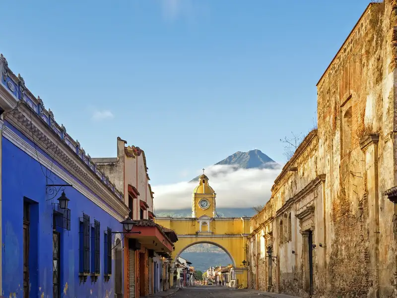 Erleben Sie auf der Studiosus-Reise nach Guatemala die koloniale Pracht Antiguas: kopfsteingepflasterte Straßen, farbenfrohe Fassaden und eindrucksvolle Kirchen und Klöster vor der Kulisse der gewaltigen Vulkane Agua, Fuego und Acatenango.