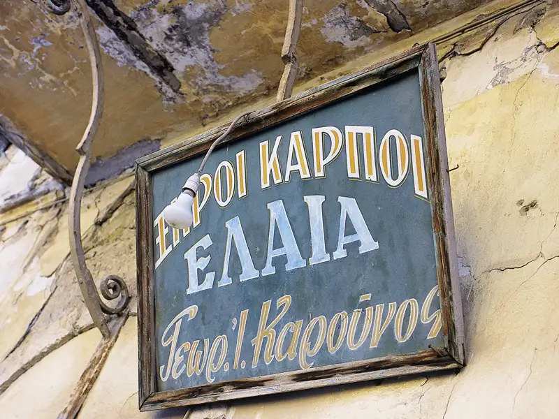 Bei unseren Rundreisen durch Griechenland in der kelinen Gruppe lenkt unser Studiosus Reiseleiter den Blick immer wieder auf kleine Details, wie hier auf ein verwittertes Ladenschild eines ehemaligen Händlers für Früchte und Olivenöl.