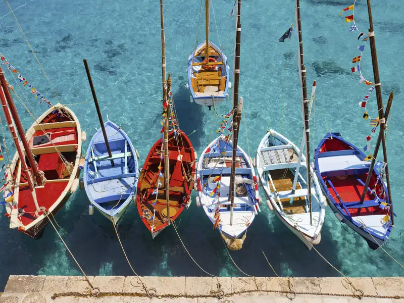 Traditionelle Fischerboote in leuchtenden Farben im Hafen. Dies und viel mehr sehen Sie auf unserer smart&small-Reise nach Apulien.