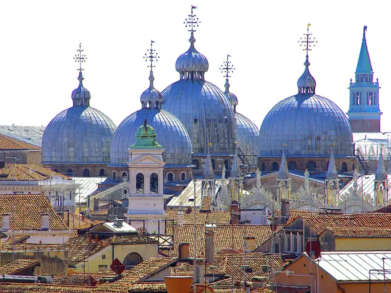 Die silbernen Kuppeln der Basilika San Marco erheben sich über den ziegelroten Dächern von Venedig. Bei der Besichtigung der Kirche erzählen Ihnen Schätze aus aller Welt von Venedig als Königin der Meere.