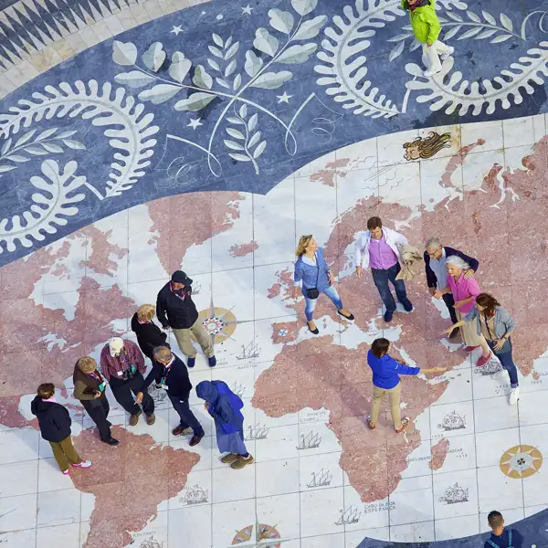 Reisegruppe auf einem Weltkarten-Mosaik, das die Reiseroute oder den globalen Kontext der Reise veranschaulicht.