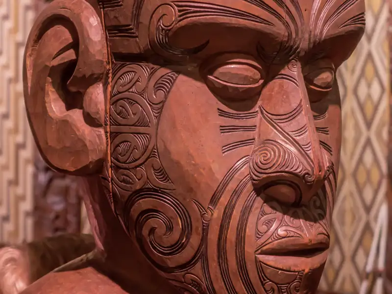 Die Versammlungshäuser (Wharenui) sind wichtig für die Kultur der Maori auf Neuseeland. Auf unserer Rundreise besuchen wir eines in Waitangi, wo diese Holzmaske zu sehen ist.