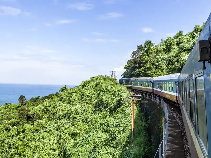Per Bus nach Da Nang, wo wir in den Zug umsteigen. Sechs Stunden machen wir den Weg zum Ziel, haben Zeit, gestenreich mit Einheimischen zu reden, während herrliches Landschaftskino am Zugfenster vorbeizieht und Händler kleine Snacks anbieten.