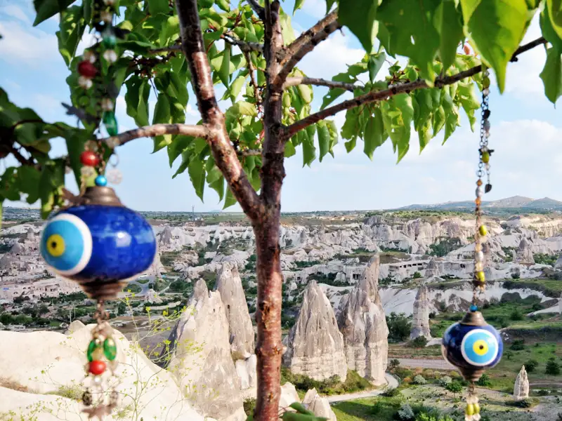 Magische Momente gibt es auf dieser achttägigen Kappadokien-Reise zuhauf. Hier der Blick auf die Feenkamine und die märchenhafte Welt im Nationalpark Göreme (UNESCO-Welterbe); im Vordergrund Glücksbringer, angelehnt an das Auge, das den bösen Blick abwehren soll.
