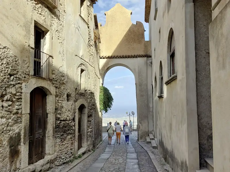 Historische Gasse in Gerace  mit Torbogen und Blick auf die Landschaft. Hier sehen Sie neben der romantischen Altstadt auch den mächtigen Dom.