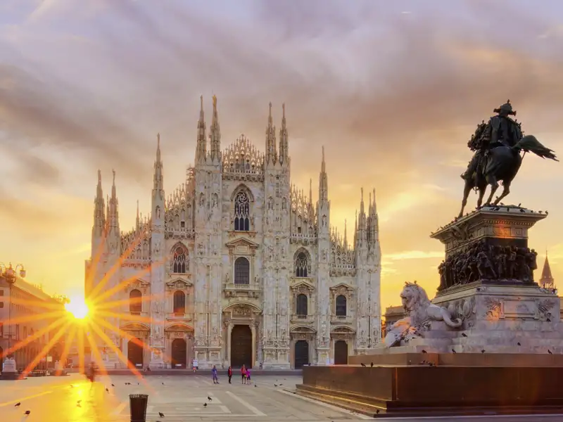 Die Piazza del Duomo bei Sonnenaufgang mit dem Mailänder Dom und dem monumentalen Reiterdenkmal für Vittorio Emanuele II., das auch "Il Cavallo di Bronzo" (Das Bronzepferd) genannt wird.