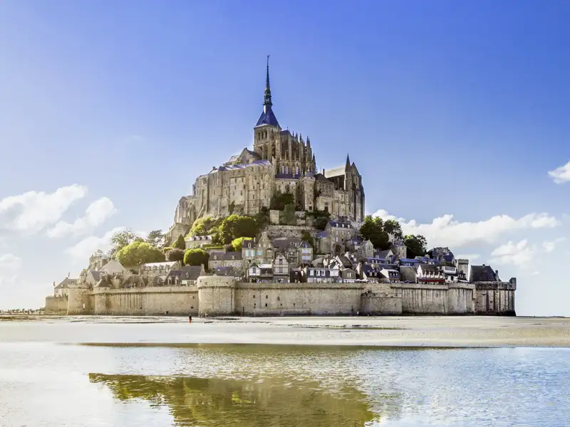 Mont Saint-Michel bei Ebbe, mit sichtbarem Sandstrand und Spiegelung im Wasser