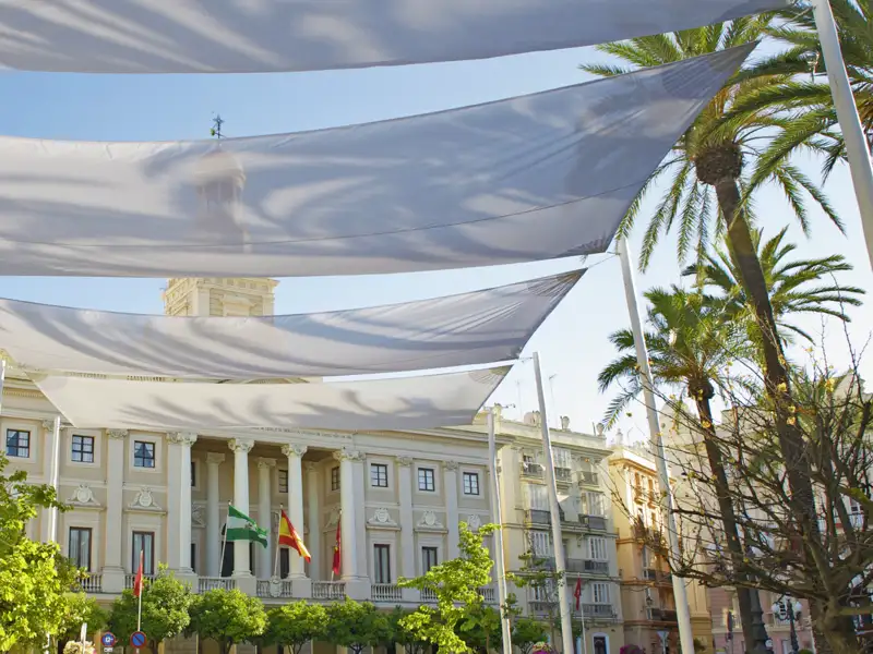 Das historische Gebäude des Rathauses von Cádiz. Auf dem Platz davor, der Plaza de San Juan de Dios, sind weiße Sonnensegel gespannt.
