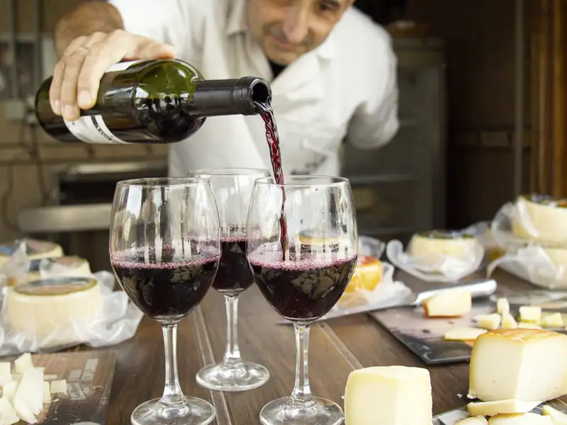 Rotwein wird eingeschenkt und Käse wird präsentiert.