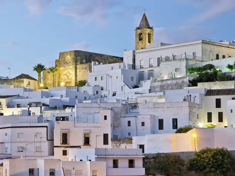 Weiße Häuser und eine Kirche in der andalusischen Stadt Vejer de la Frontera bei Dämmerung