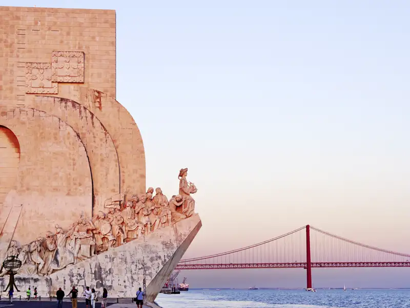 DasPadrão dos Descobrimentos, ein Denkmal für die portugiesischen Entdecker, steht am Ufer des Tejo in Belém, Lissabon. Im Hintergrund ist die Ponte 25 de Abril zu sehen. Hier halten wir für einen Fotostopp auf unserer Reise durch Portugal.