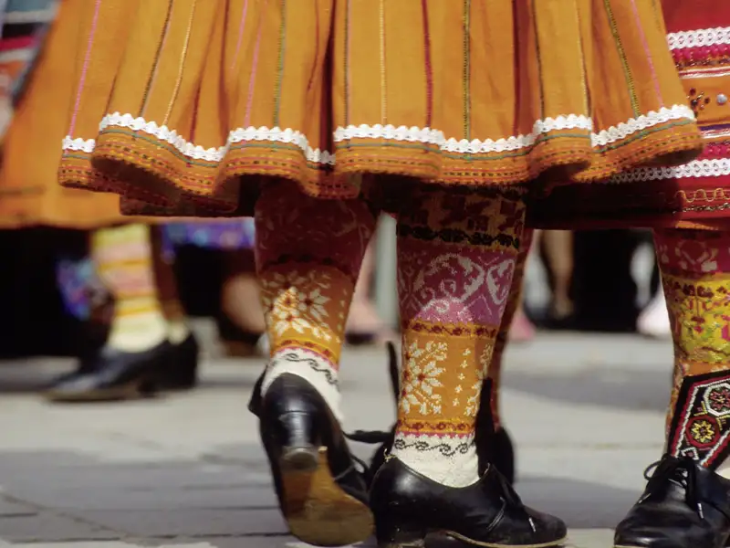 Detailansicht einer traditionellen Tracht Lettlands mit bunten und auffällig gemusterten Röcken und Strümpfen