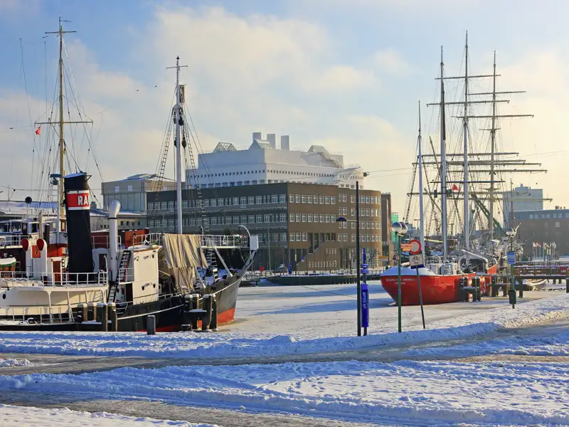 Auf Ihrer Gruppenreise nach Bremen sehen wir Historische Schiffe im Winter im verschneiten Hafen.