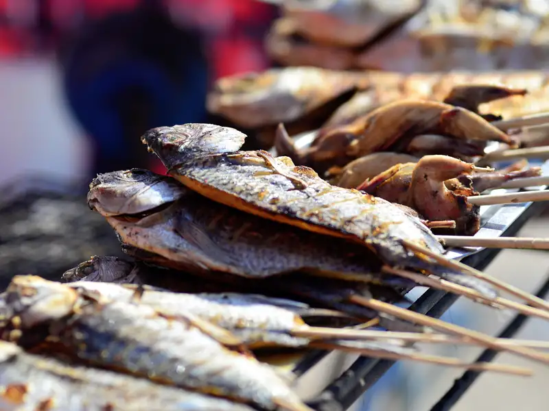 Gegrillter Fisch auf Spießen, ein Beispiel für die authentische lokale Küche, die Reisende während der Tour entdecken können.