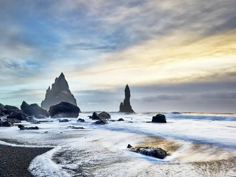 Die markanten Felsnadeln Reynisdranga am schwarzen Sandstrand von Reynisfjara. Bei dieser Reise ist dies ein im Reiseverlauf geplanter Stopp an Islands Südküste.