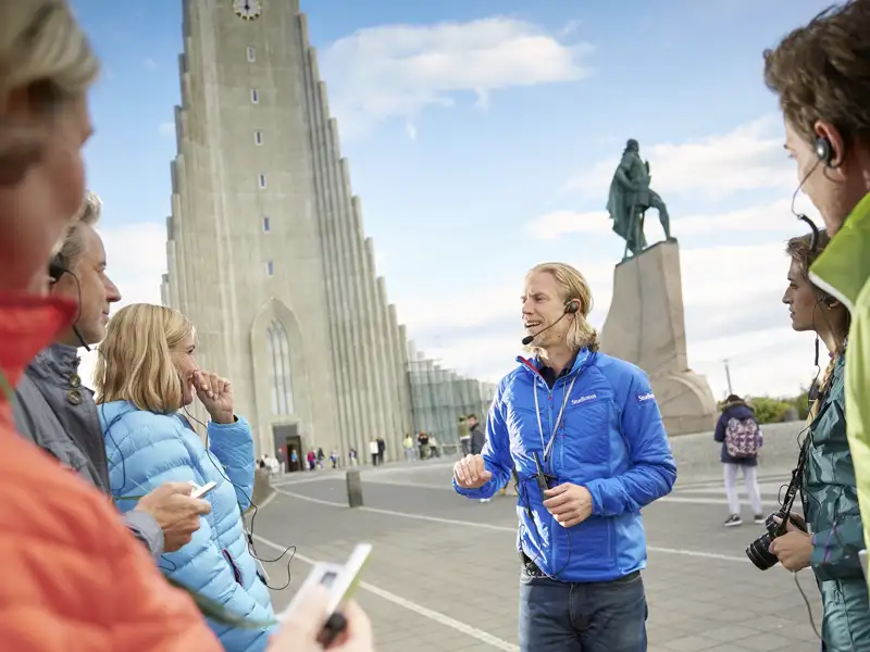 Studiosus-Reiseleiter erklärt einer Reisegruppe die Sehenswürdigkeiten vor der Hallgrimskirche in Reykjavik. Ein tolles Erlebnis jeder Gruppenreise nach Island.