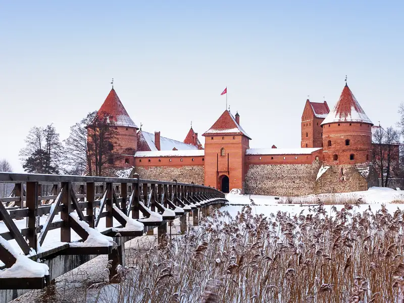 Die rote Backsteinburg Trakai in einer verschneiten Winterlandschaft, ein im Reiseverlauf inkludierter Programmpunkt  dieser Reise.