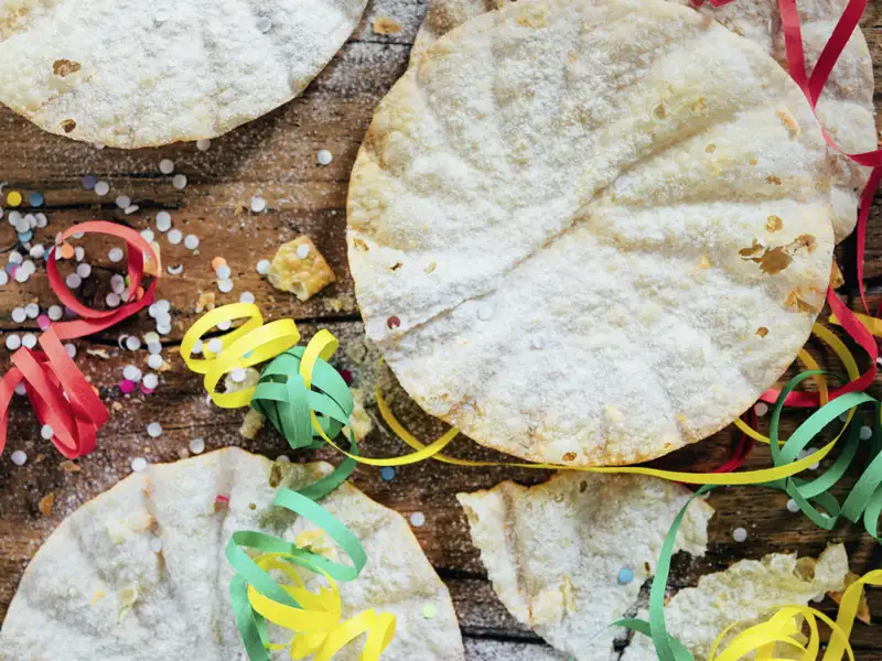 Auf unserer Gruppenreise mit Studiosus lassen wir uns von traditionellem, süßem Karnevalsgebäck mit Puderzucker und Luftschlangen verwöhnen. Sie heißen Fasnachtküchlein.