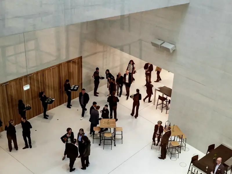 Die Gäste unserer Gruppenreise netzwerken auf einer Veranstaltung im Foyer. Mehrere Servicekräfte tragen Tabletts mit Getränken und Speisen.