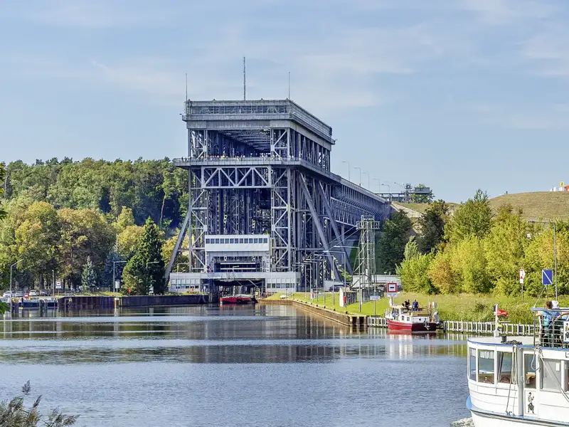 Auf unserer Kreuzfahrt mit Studiosus fahren wir durch das historische Schiffshebewerk Niederfinow, umgeben von grünen Wäldern an einem sonnigen Tag. Ein Highlight jeder Rundreise in Brandenburg.
