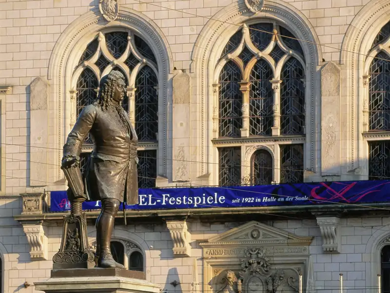 Händel-Denkmal auf dem Hauptmarkt in Halle mit Banner der Händel-Festspiele vor der historischen Fassade der Marktkirche, ein Highlight jeder Studiosus Gruppenreise.