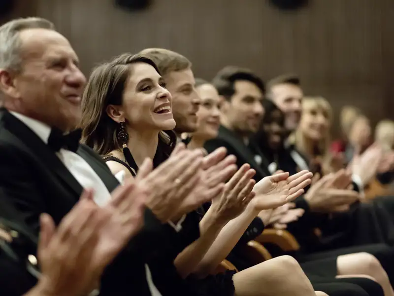 Elegant gekleidete Reisegäste klatschen als Publikum bei einer Abendvorstellung, die wir auf unserer Eventreise mit Studiosus besuchen.