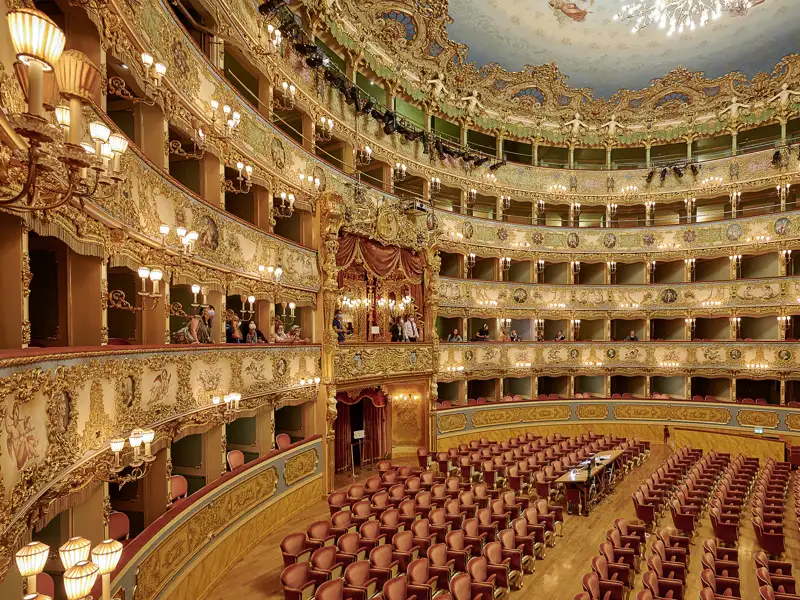 Auf unserer Gruppenreise mit Studiosus erleben wir den opulenten Innenraum des Teatro La Fenice in Venedig. Ein Highlight der Eventreise sind die goldverzierten Logenränge und die roten Sitze des Opernhauses.